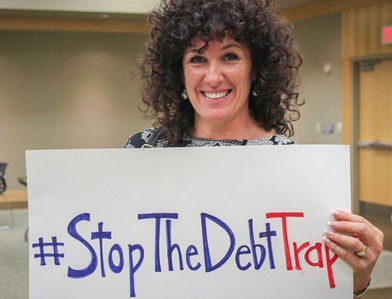 woman holding sign that says "Stop the Debt Trap"